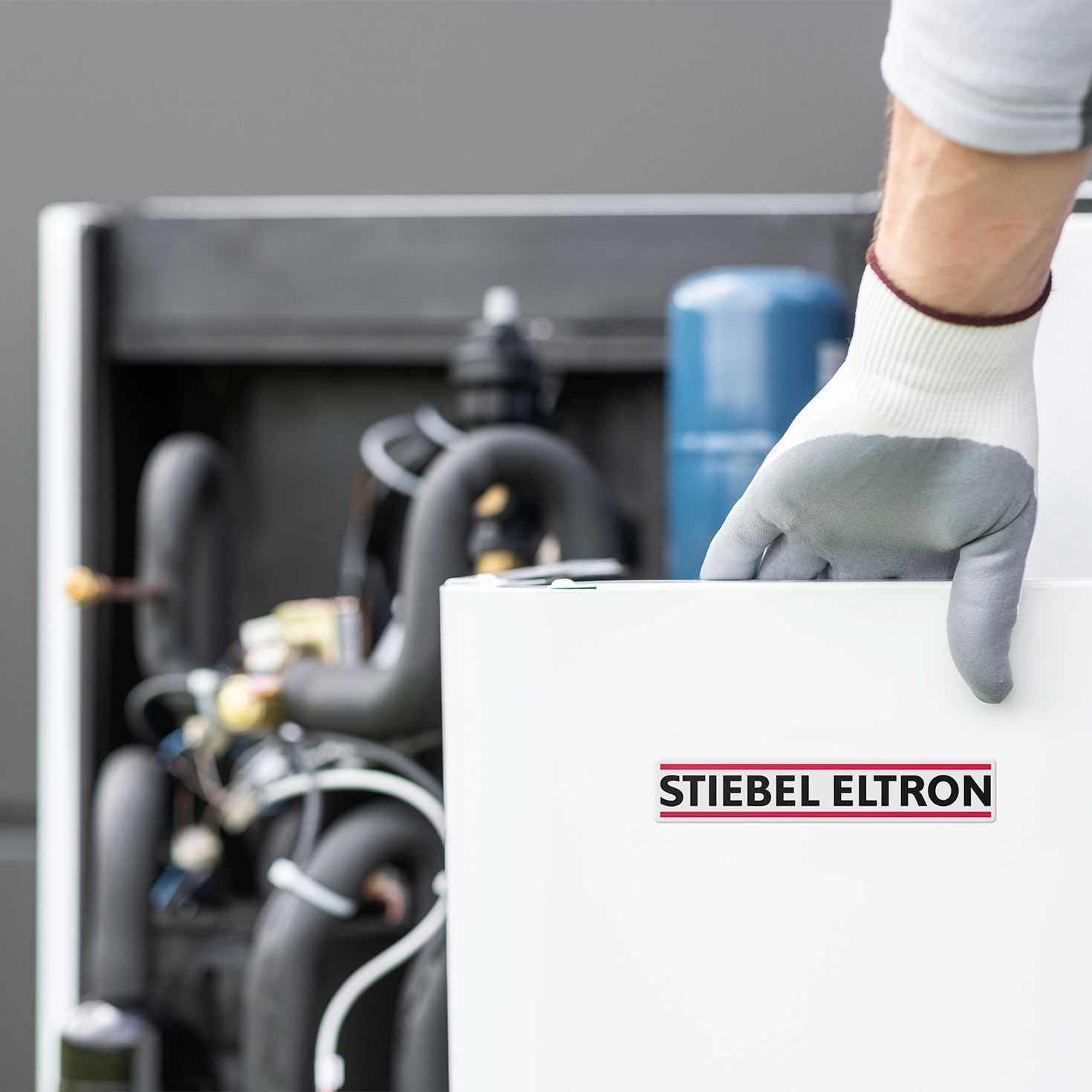 Hand mit Handschuh häjt Verkleidung einer STIEBEL ELTRON-Wärmepumpe